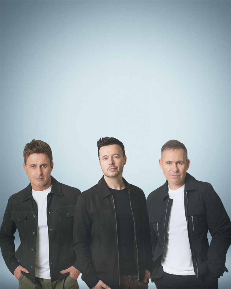 Three men wearing black jackets standing in front of a grey background.