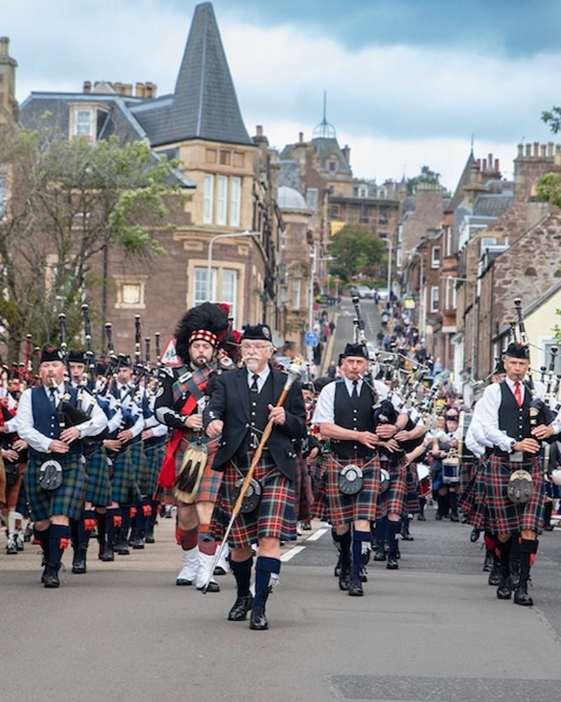 Pipe band marching, wearing Kilts and Scottish attire down Market street in Crieff