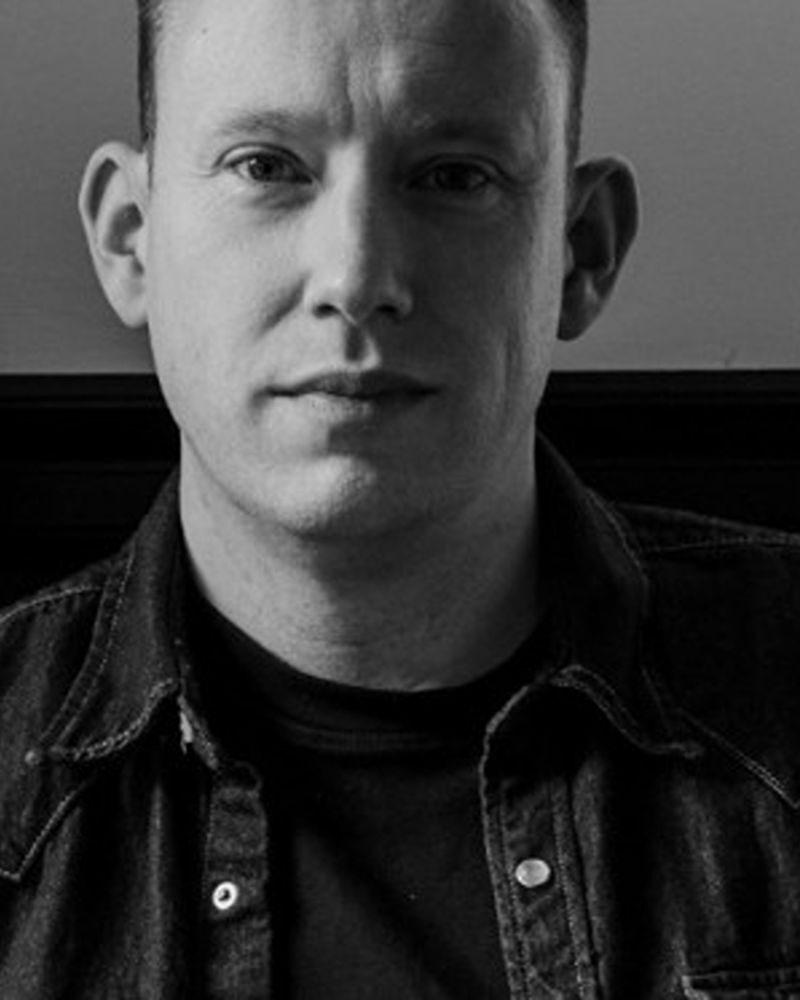 Black and white picture of a man staring solemnly into camera