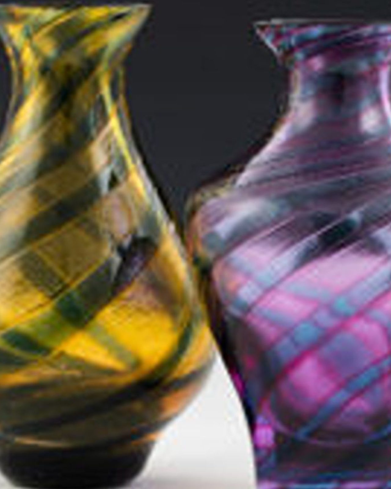 A yellow patterned glass vase sits next to a purple patterned glass vase