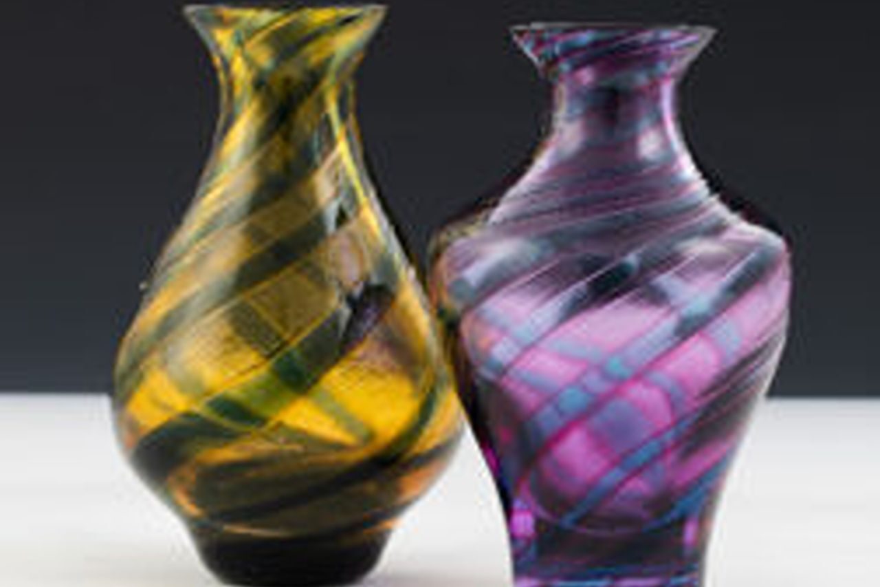 A yellow patterned glass vase sits next to a purple patterned glass vase