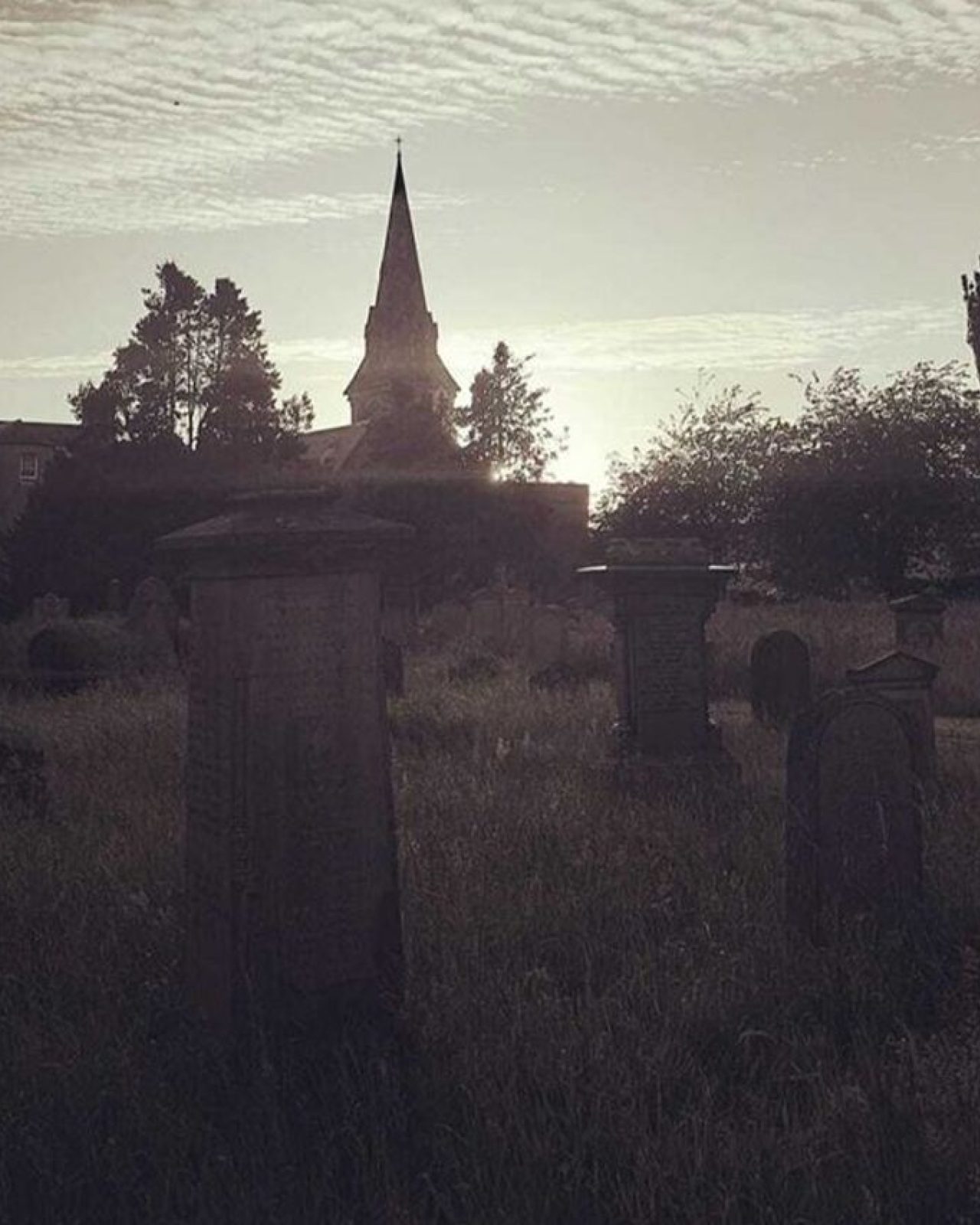 A dimly lit burial ground with several carved headstones