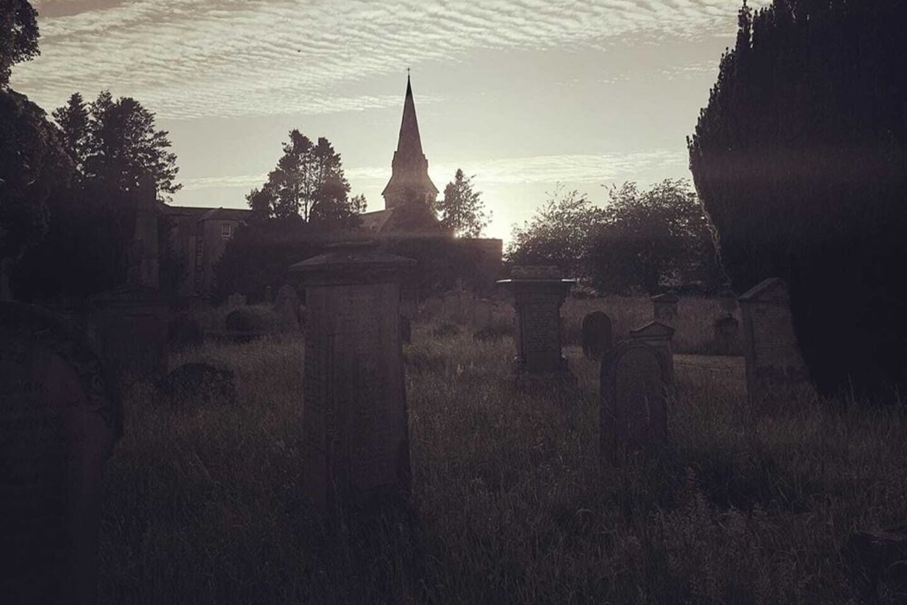 A dimly lit burial ground with several carved headstones