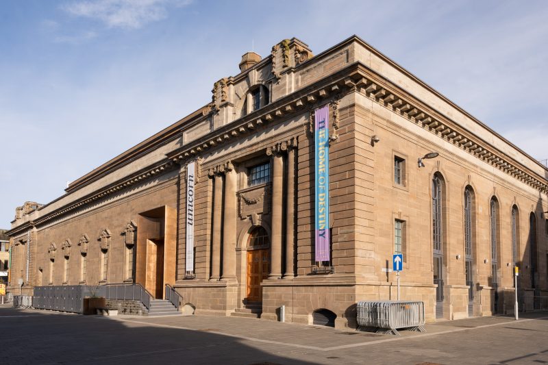 A large stone building with intricate stone details and colourful banners