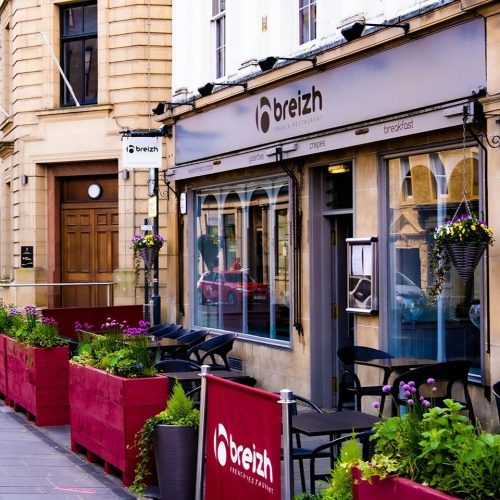 A restaurant in Perth with purple windows, door, and sign and an outdoor seating area decorated with purple flowers in pink pots