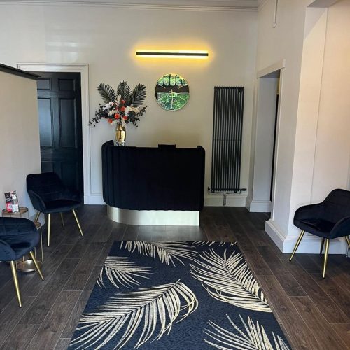 A room with white walls filled with dark blue and gold furniture including chairs, a reception desk, and a rug with feathers.