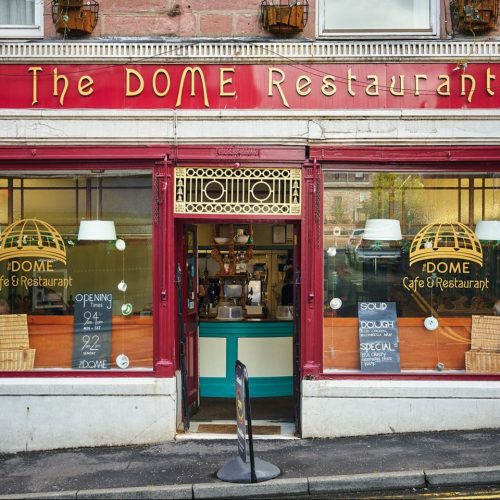 The Dome restaurant has large red decorated windows either side of an open door which exposes a blue and white interior.
