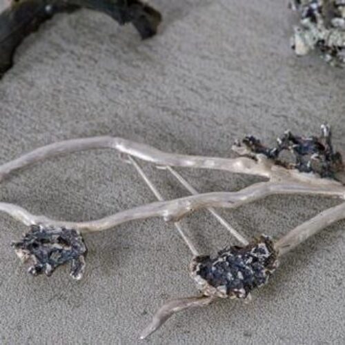A small delicate broach with three white branches decorated with three small grey stones