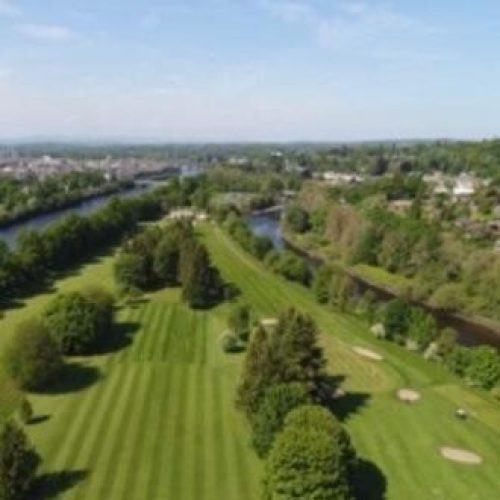 A large open golf course covered in large green trees sitting on an island in the River Tay in Perth