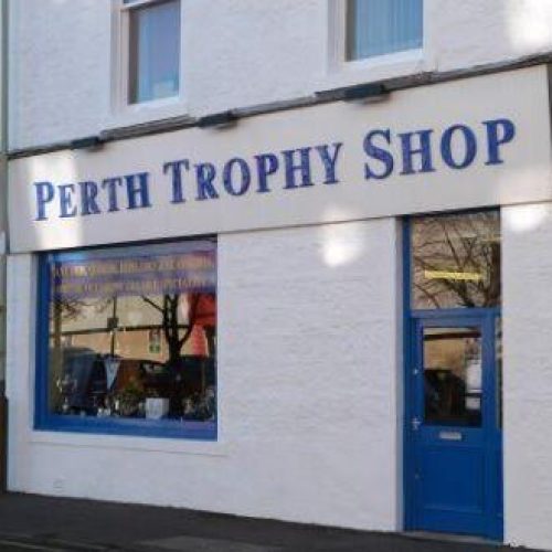 A large white sign with blue writing reading Perth Trophy Shop sits above a window displaying several different trophies