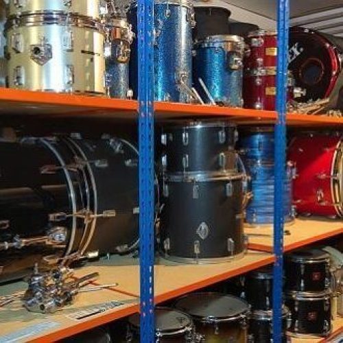 Large shelves holding dismantled drum kits ranging in size and colour