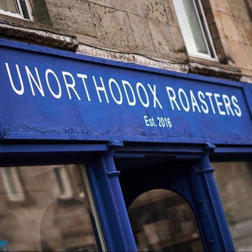 A dark blue sign with white font above a door and two windows