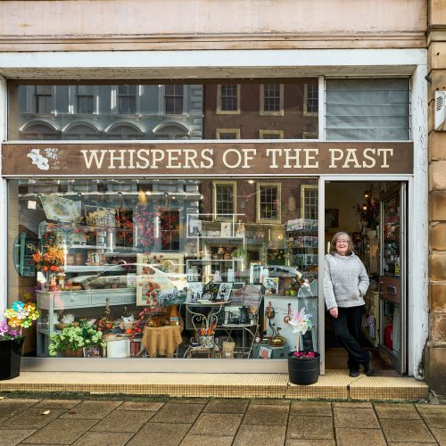 Whispers of the Past shop on George Street in Perth with a woman standing in the doorway by a large window display