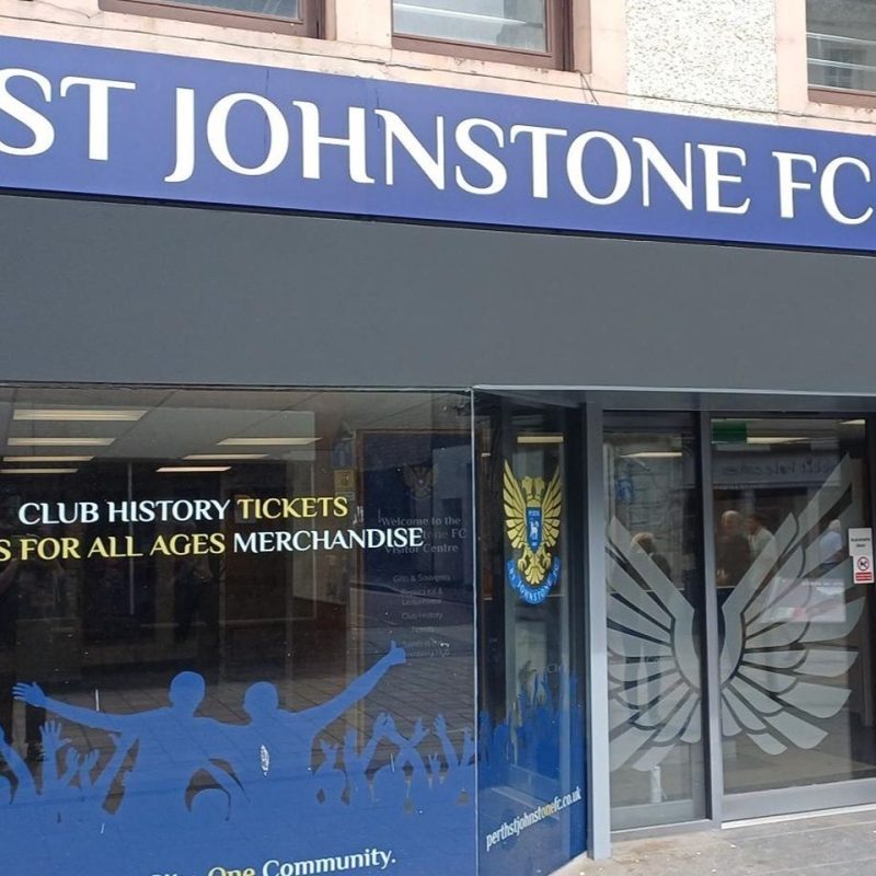 A shop in Perth with a blue sign and white font above a window decorated with blue silhouettes and a football club logo