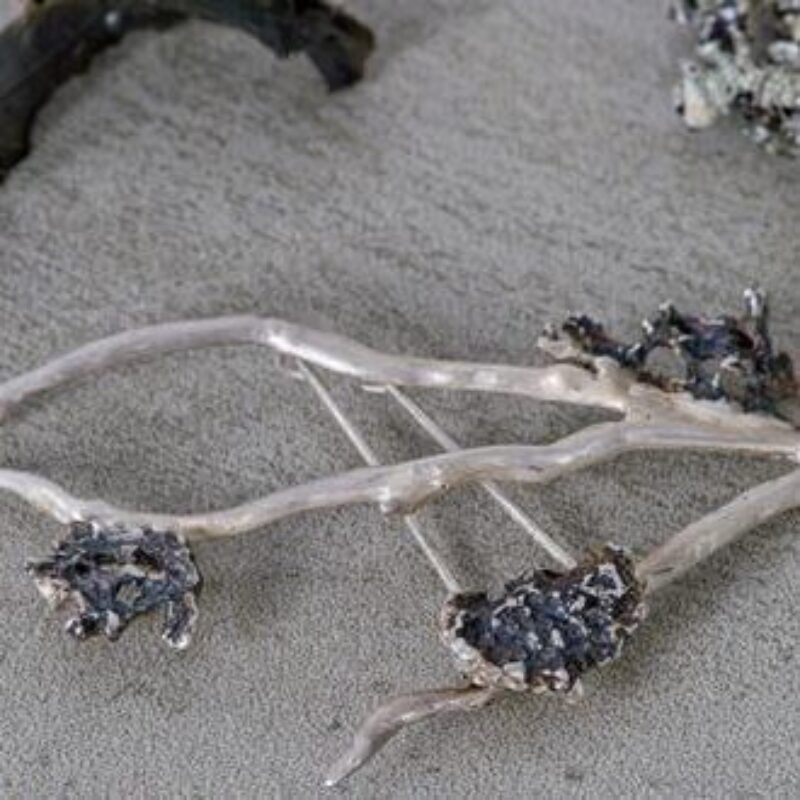 A small delicate broach with three white branches decorated with three small grey stones
