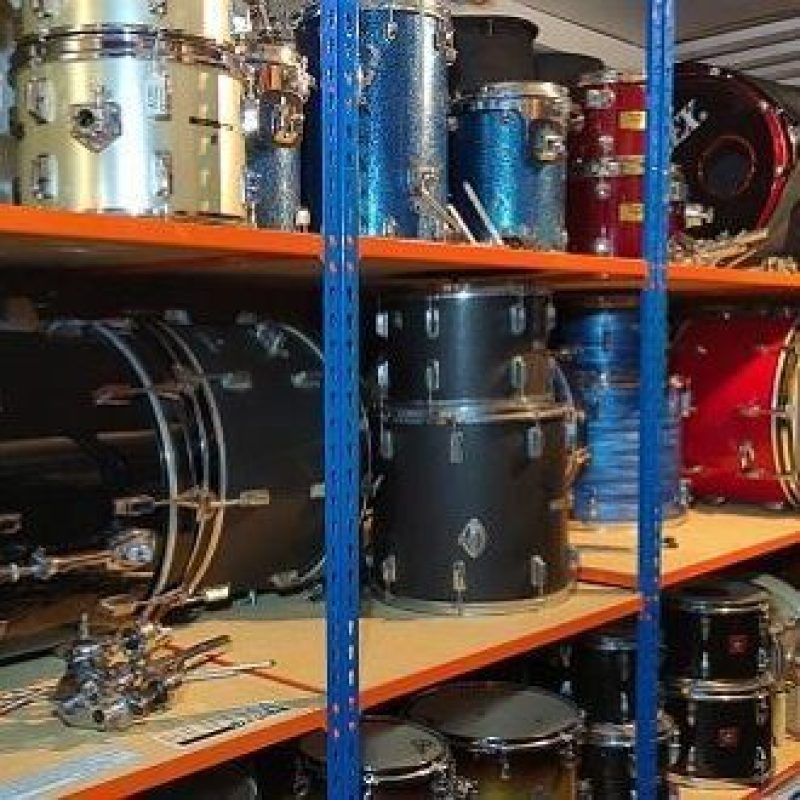 Large shelves holding dismantled drum kits ranging in size and colour