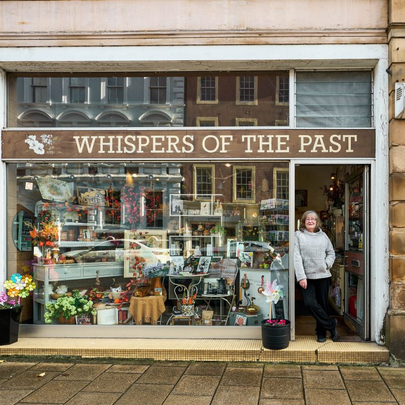 Whispers of the Past shop on George Street in Perth with a woman standing in the doorway by a large window display